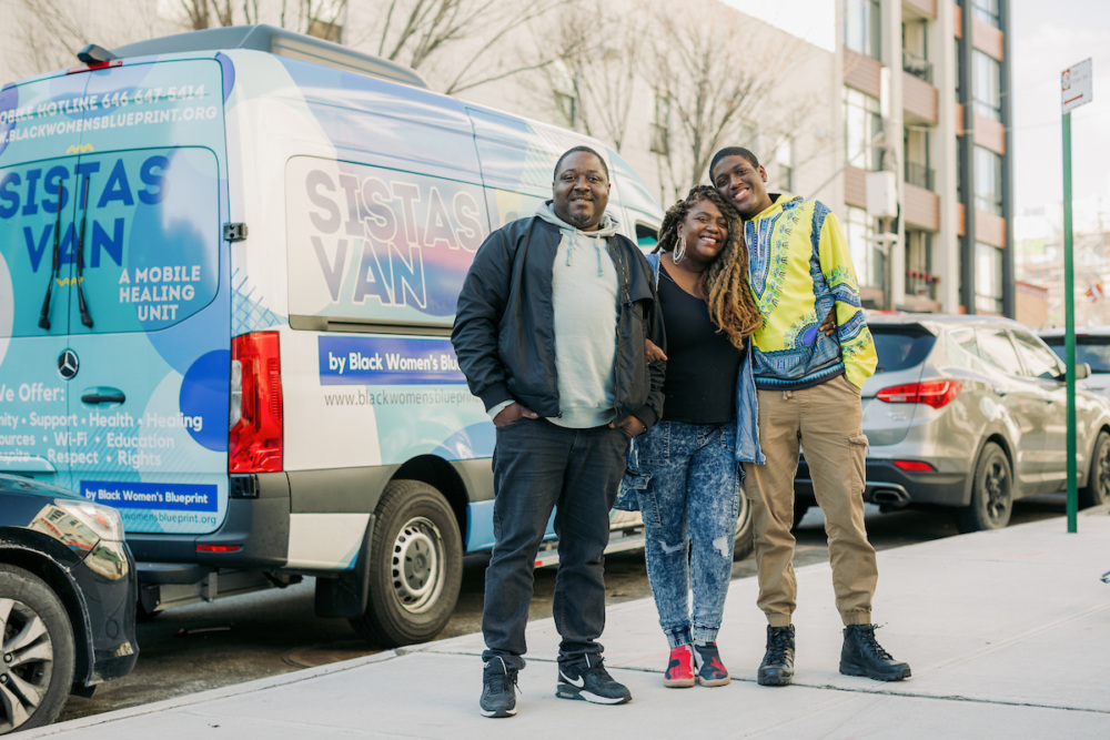 A group of people standing in front of a van.