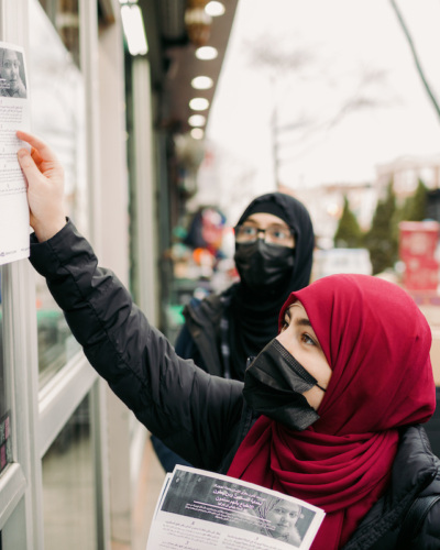 Two hijabi women distribute flyers on the street