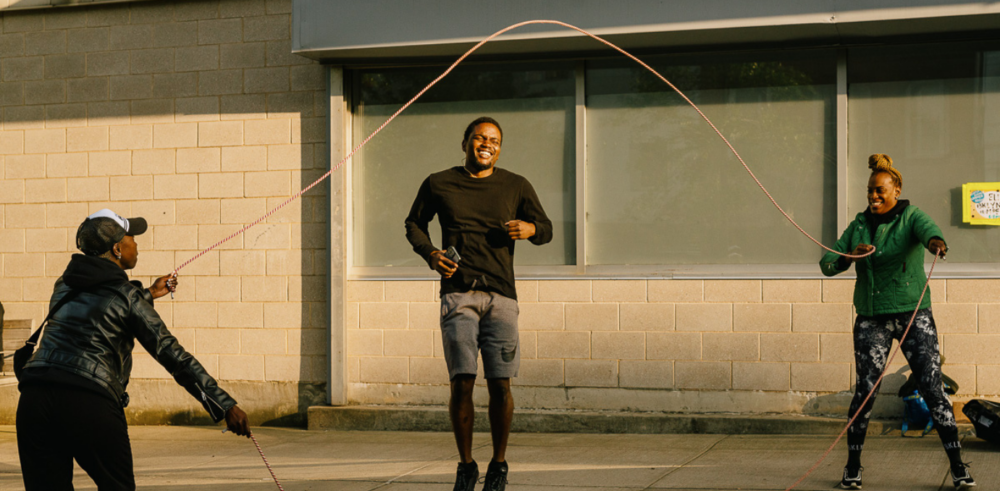 A group of people playing with skipping ropes in front of a building.