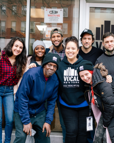 A diverse group of people pose for a photo outside of VOCAL New York's office in Brooklyn.
