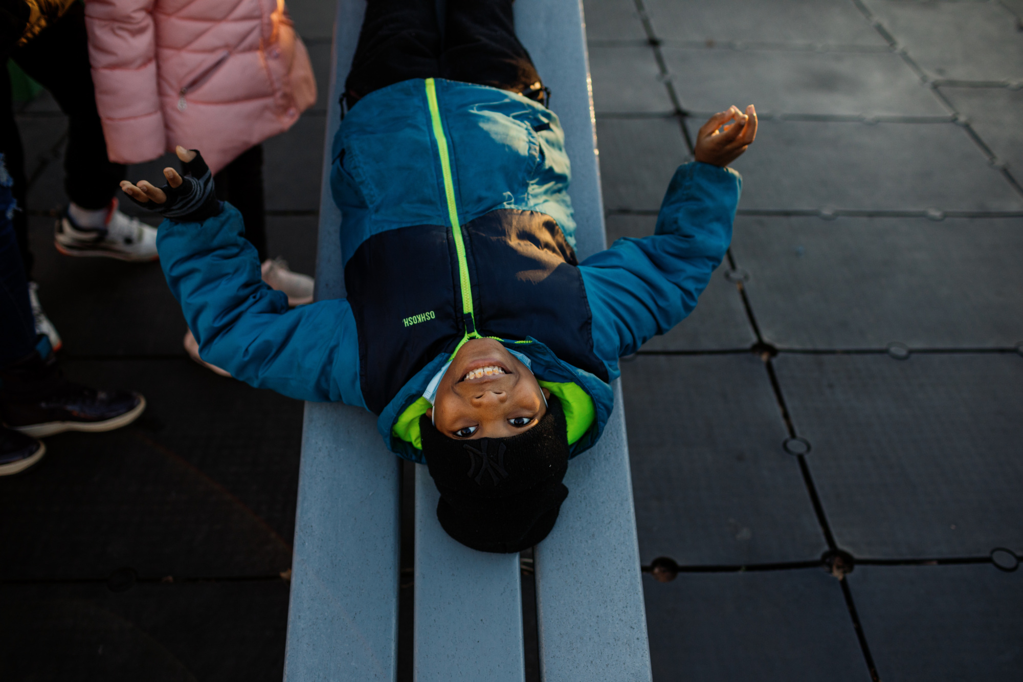 A boy laying on a bench.