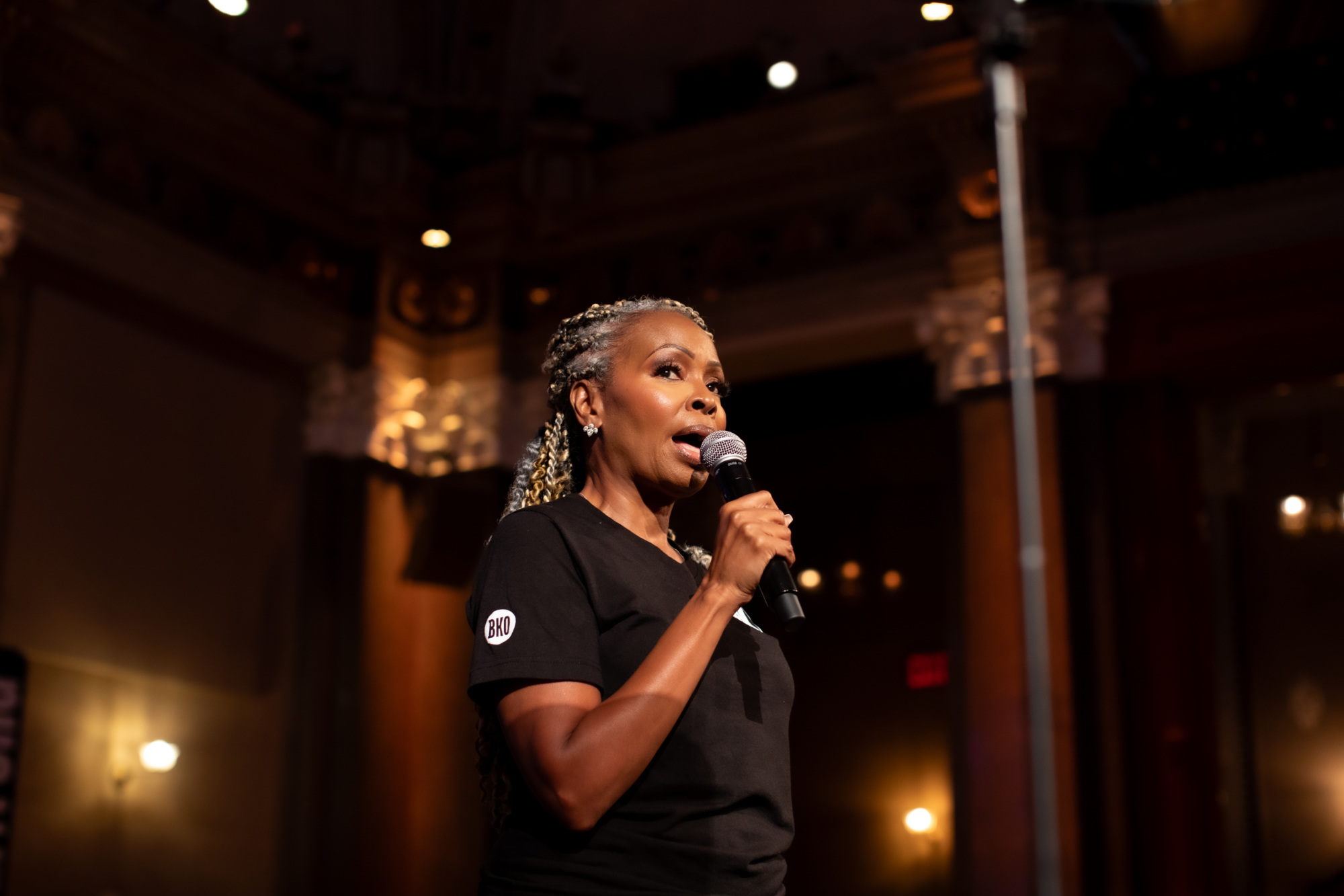 A woman in a black shirt is speaking into a microphone.