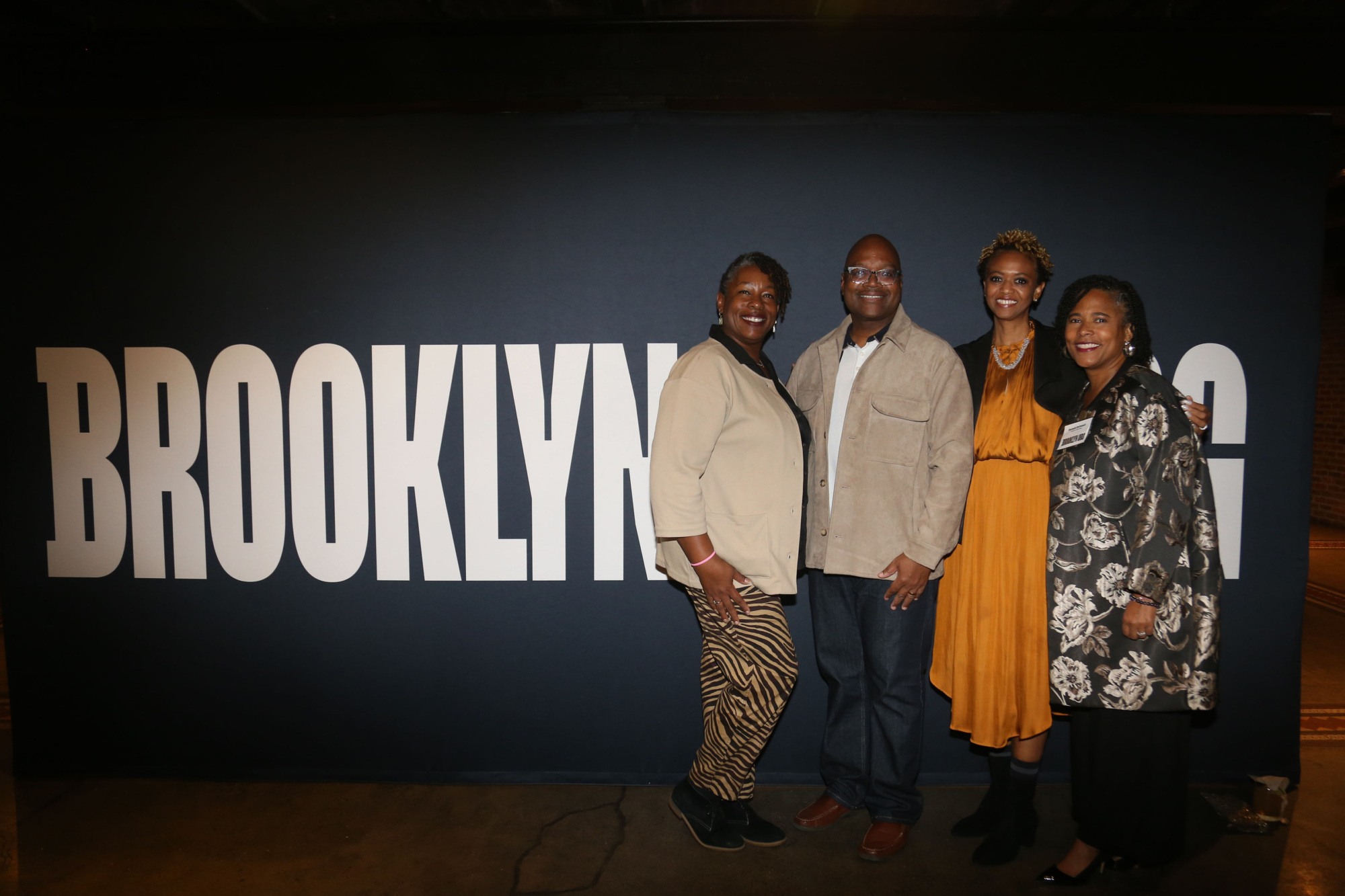 Four people standing in front of a brooklyn sign.