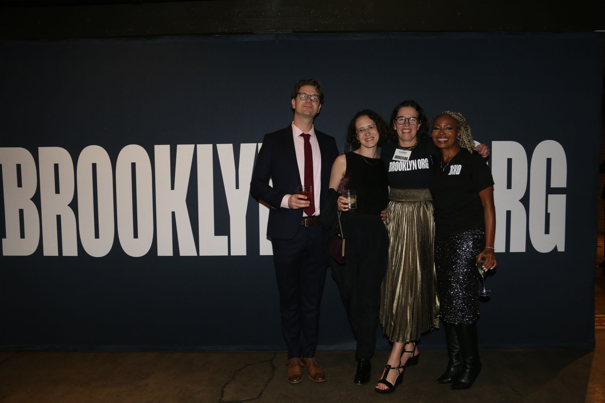 A group of people posing in front of a sign that says brooklyn org.