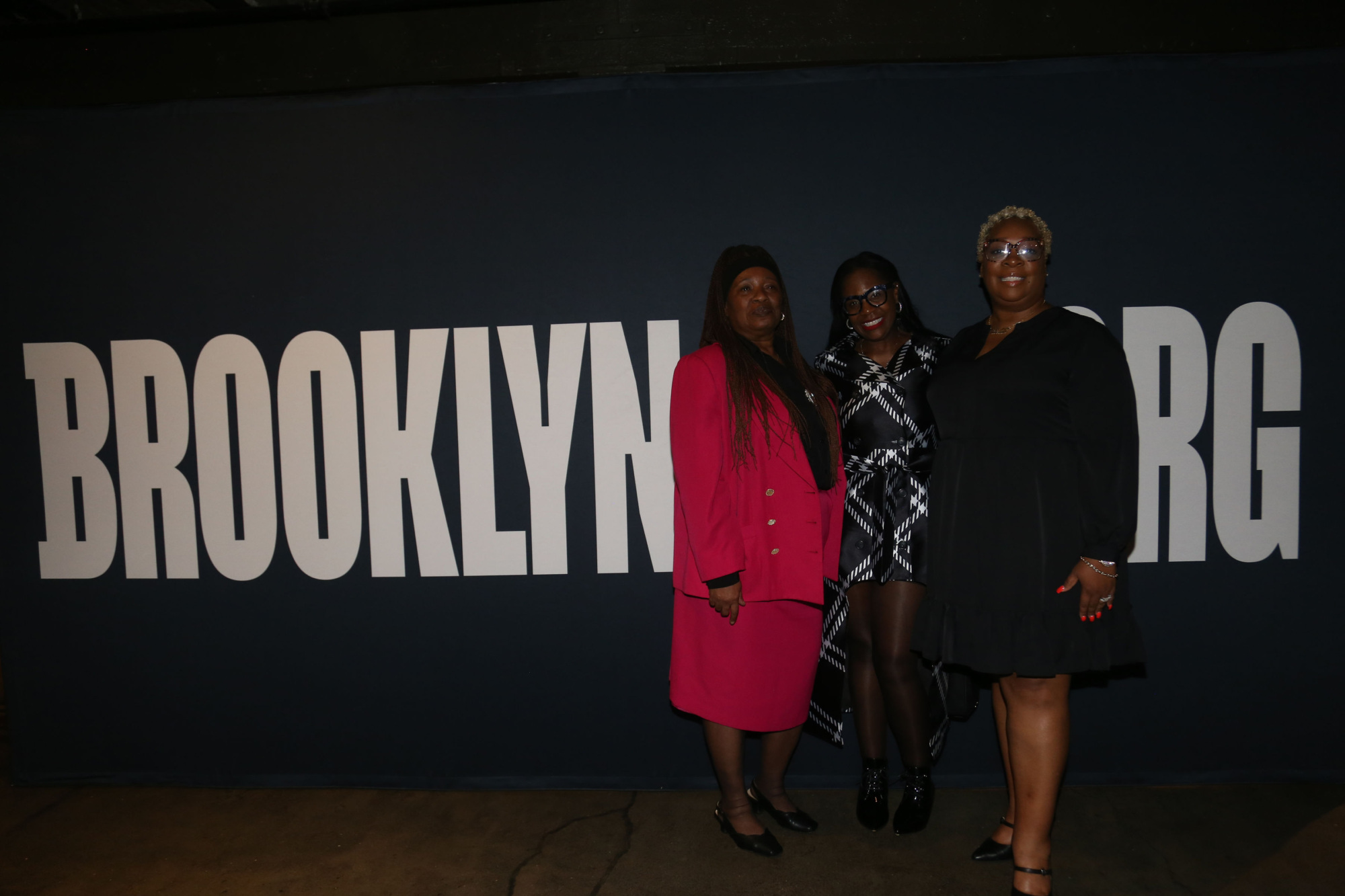 Three women standing in front of the brooklyn bg sign.