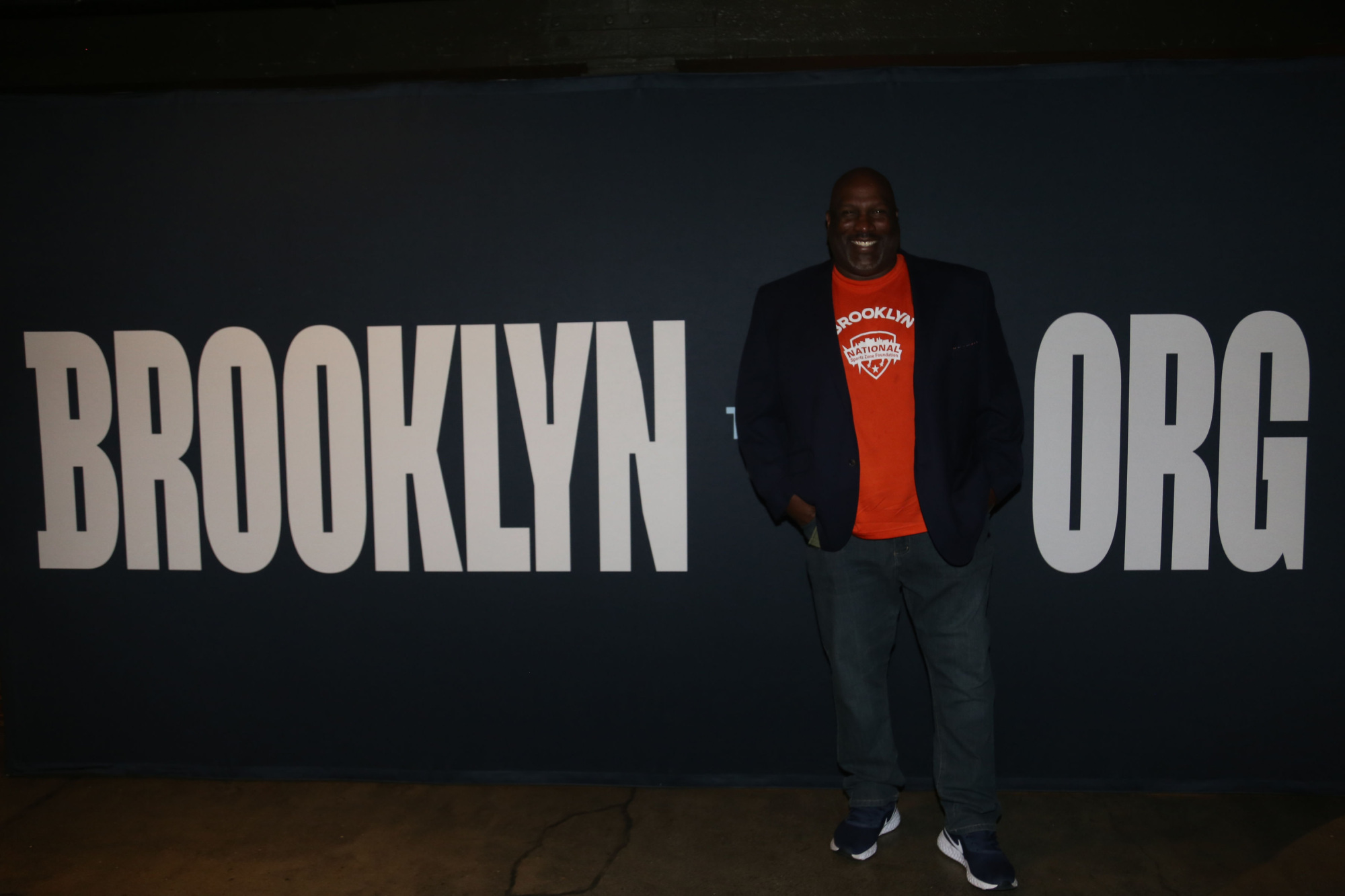 A man standing in front of a sign that says brooklyn org.