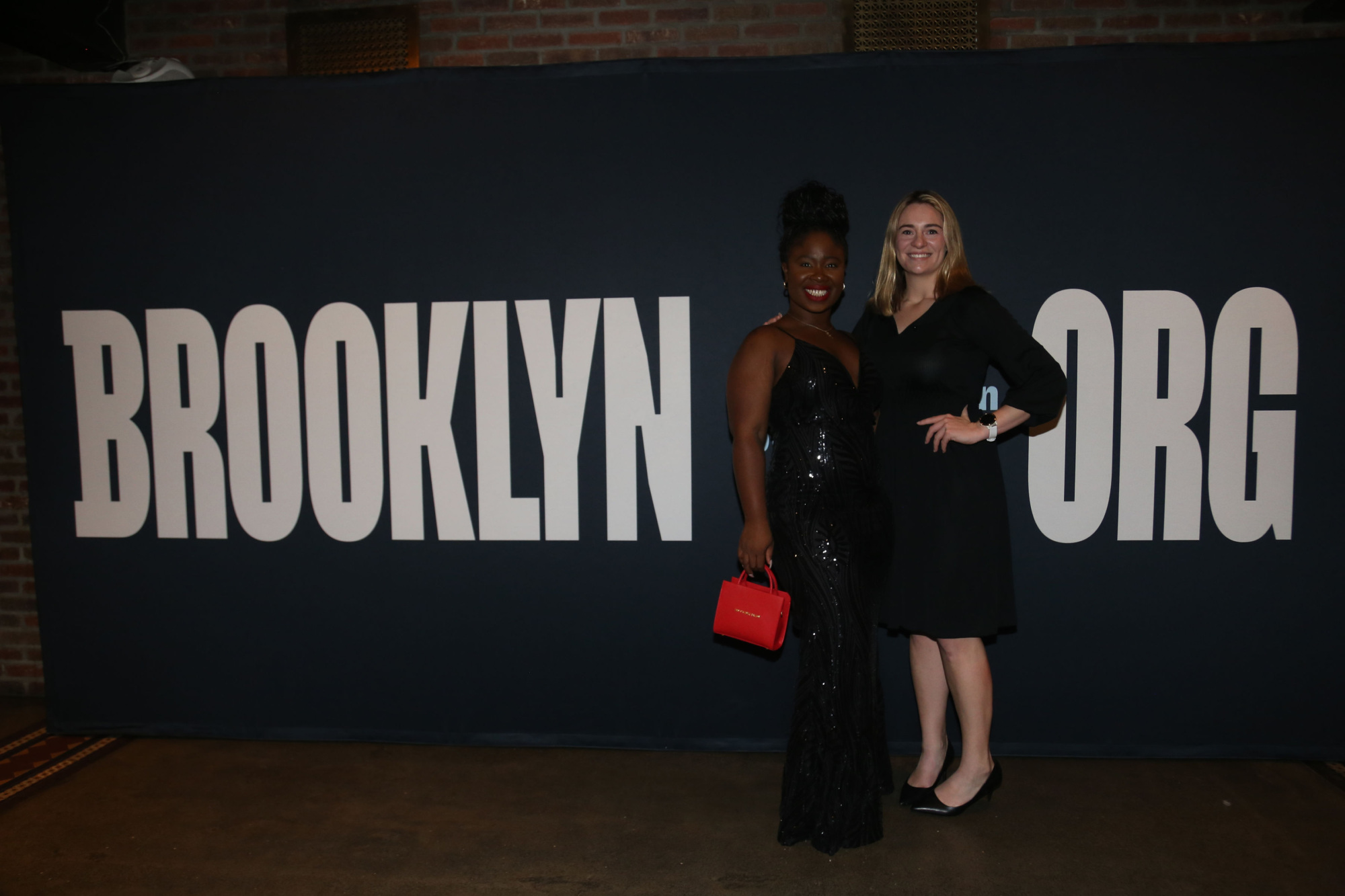 Two women standing in front of the brooklyn org sign.