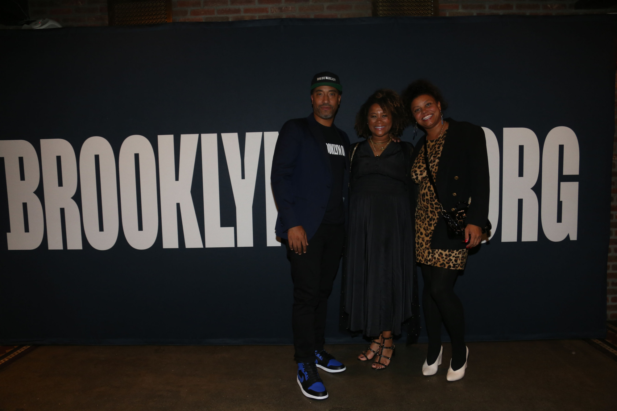 Three people standing in front of the brooklyn org sign.