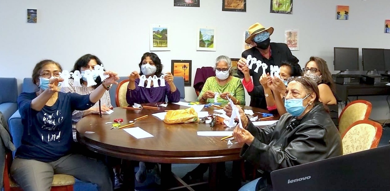 A group of people sitting around a table with masks on.