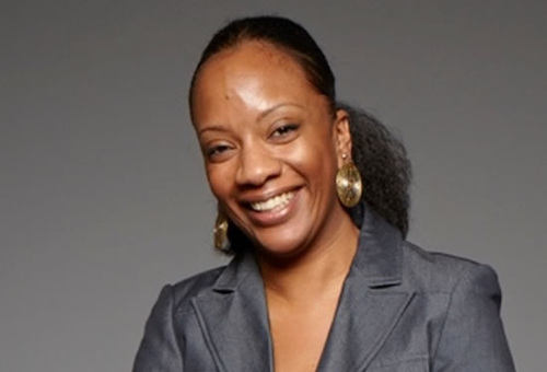 A black woman smiling in a gray suit.