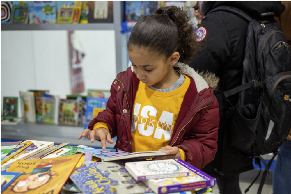 A young girl is reading a book at a book fair.