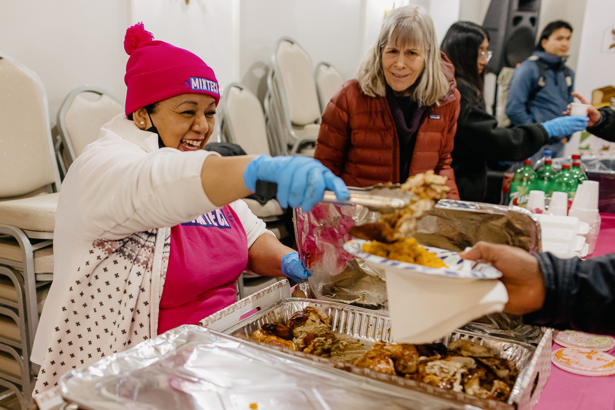 A woman is serving food to a group of people.