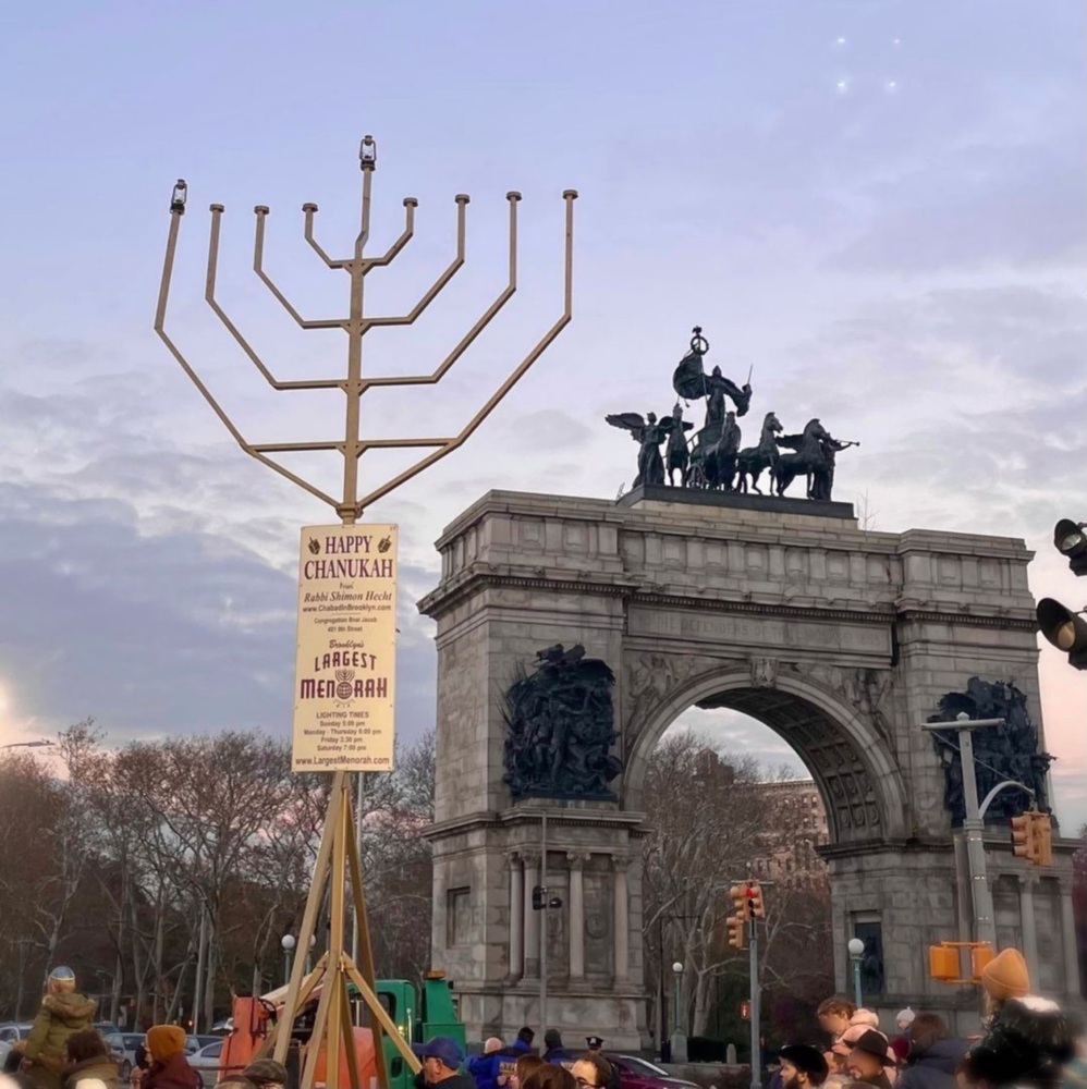 A large menorah in the middle of a crowd of people at Grand Army Plaza, Brooklyn.