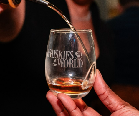 A person pouring whisky into a glass.