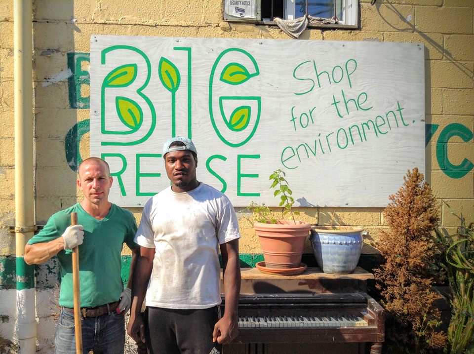 Two men standing in front of a sign that says big rese for the environment.