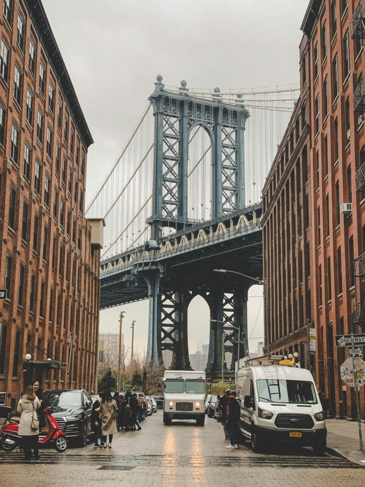 The Manhattan bridge is in the background of a city street.