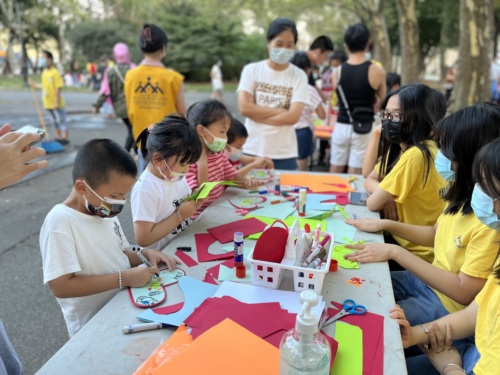 A group of people sitting at a table with paper crafts.