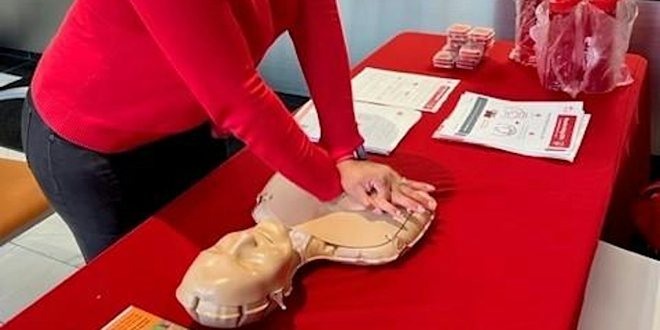 A person is practicing CPR on a dummy on a table.