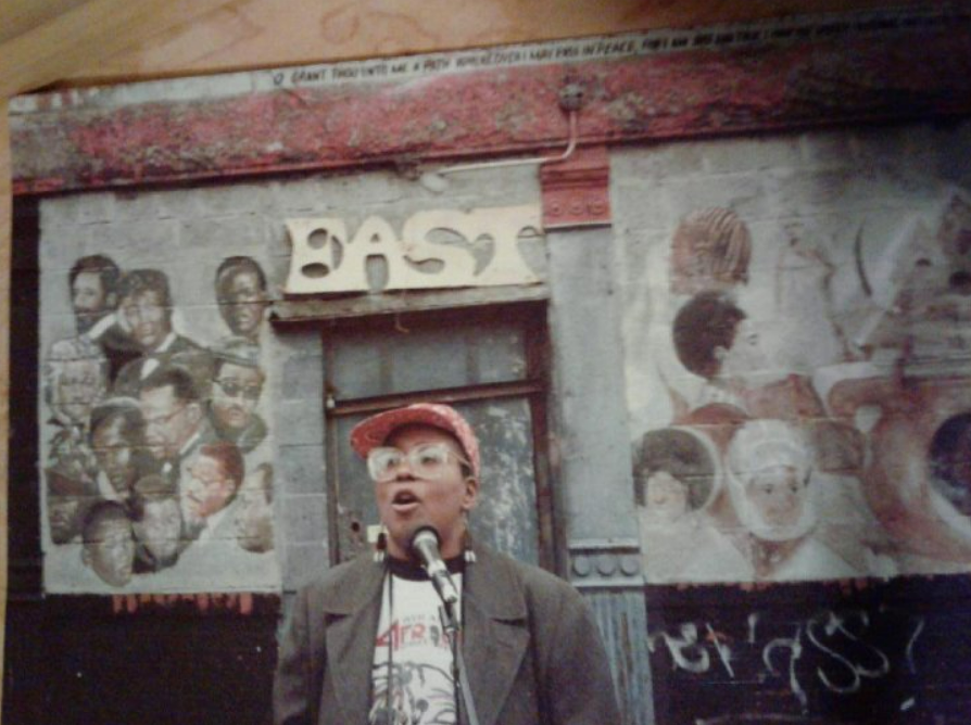 A man is standing in front of a wall with graffiti on it.