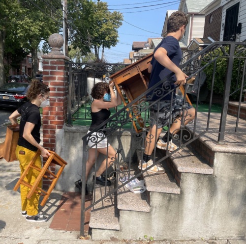 A group of people moving furniture up a set of stairs.