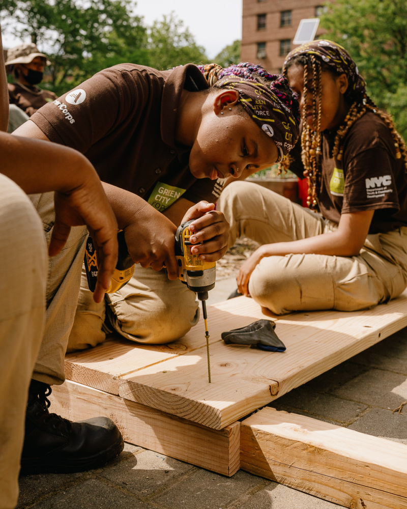 A group of girls working on a piece of wood.