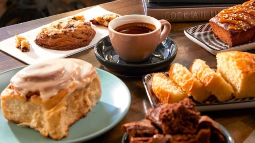 A table with a variety of pastries and a cup of coffee.