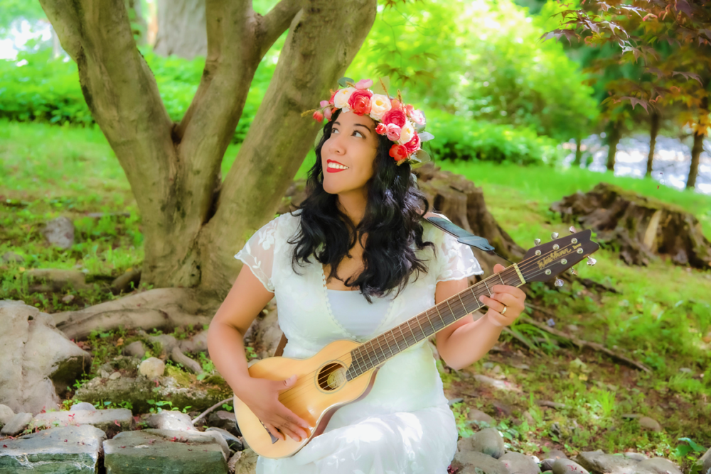 A woman in a white dress playing a guitar.