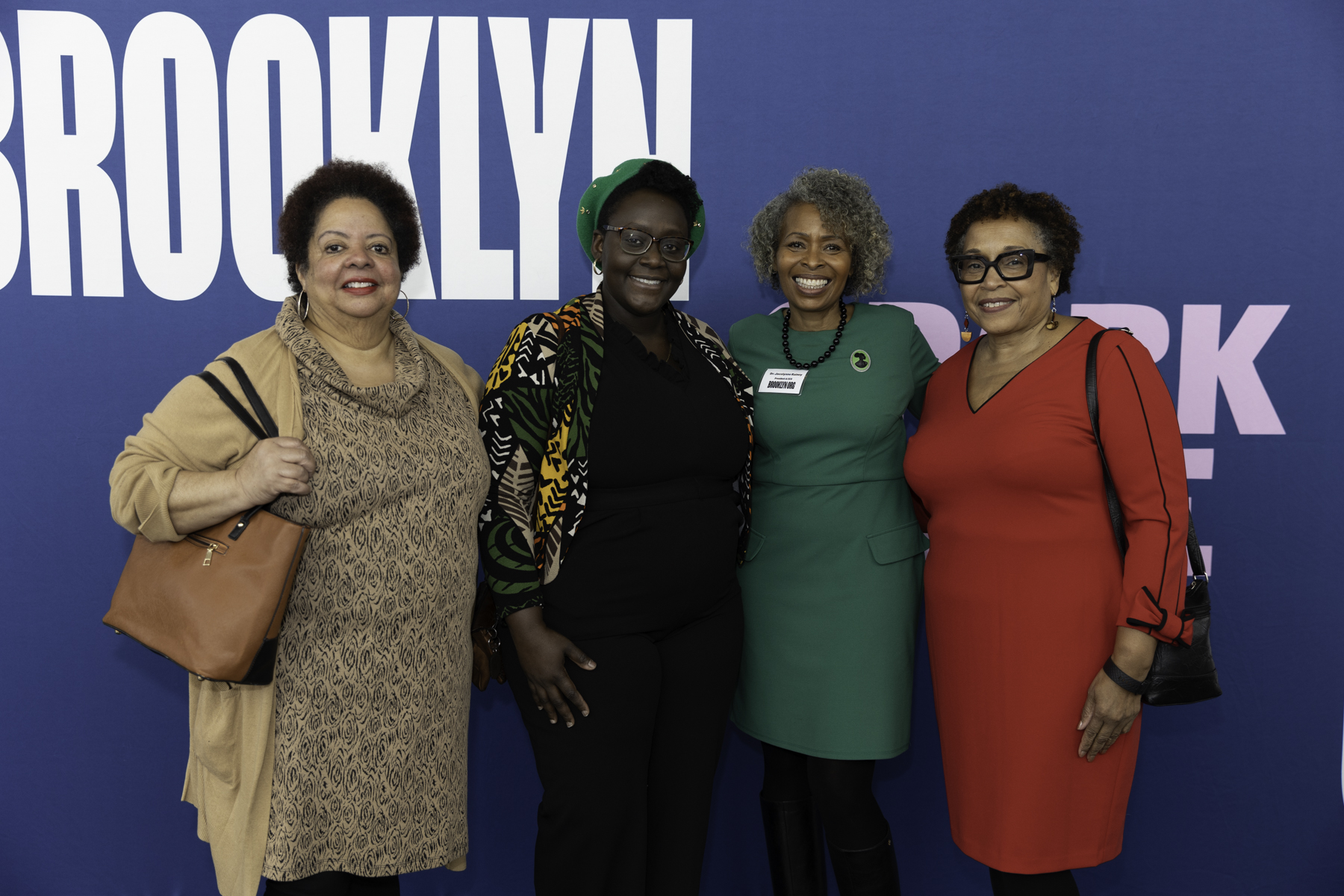 Four women smiling for a photo at a brooklyn event.