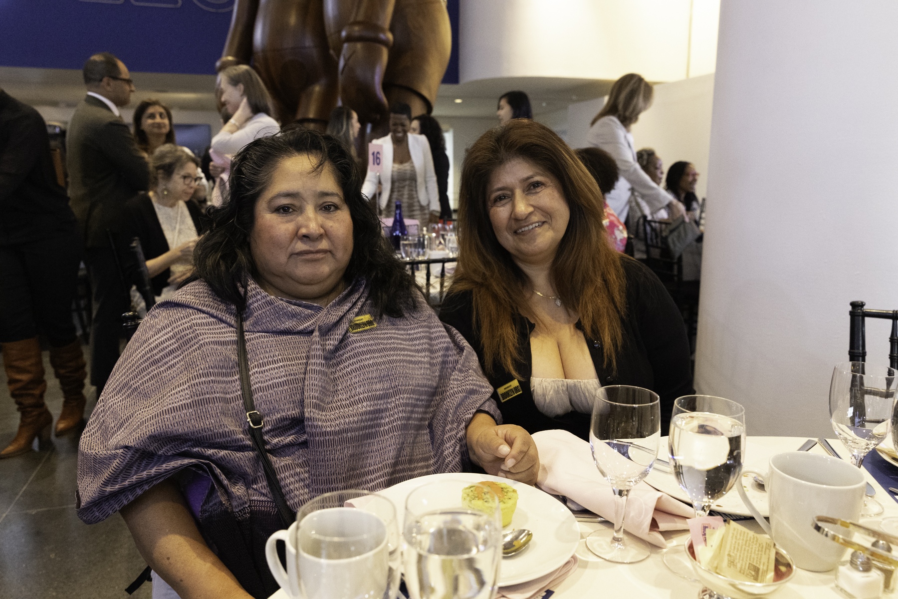 Two women sitting at a dining table during an event.