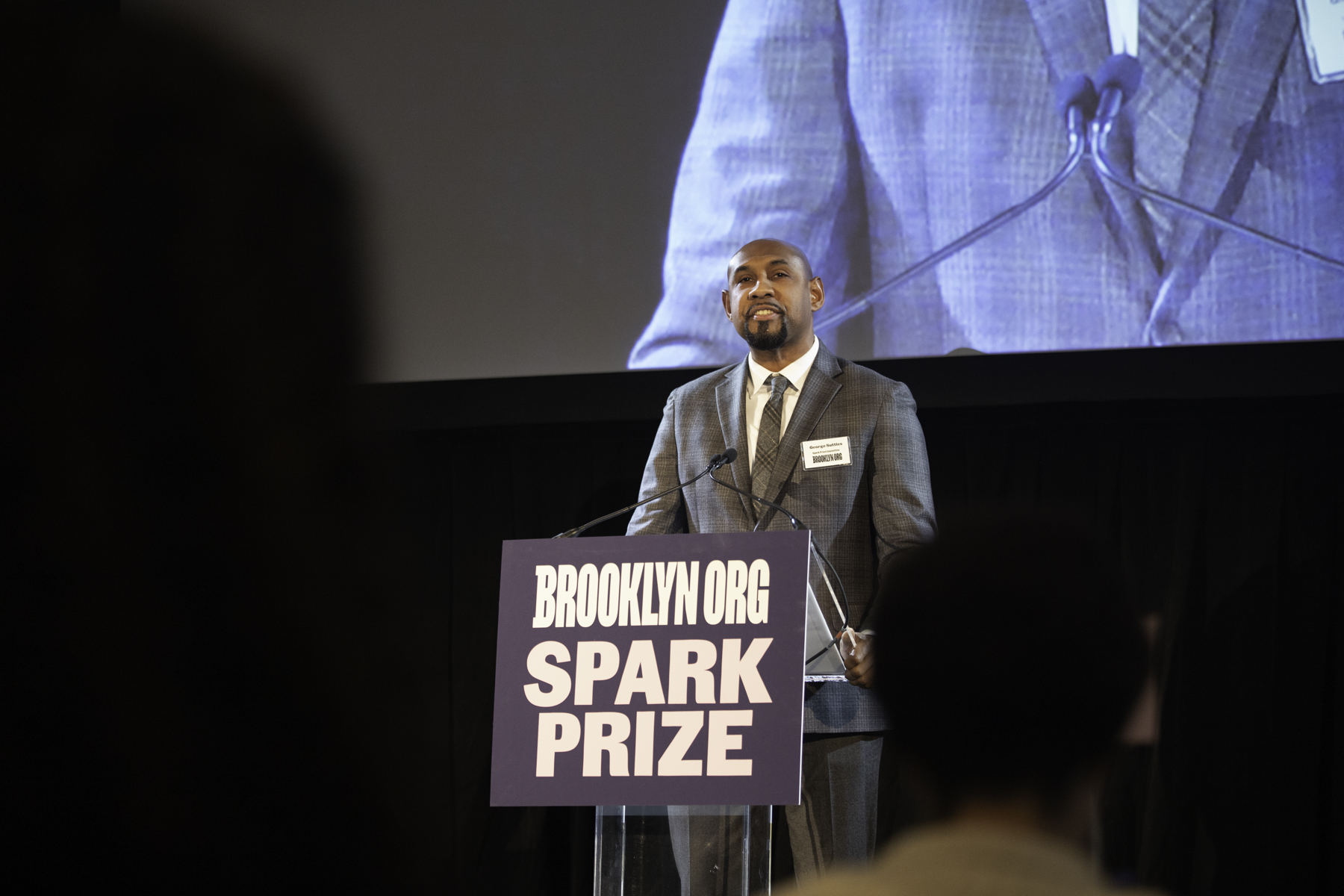 A man delivering a speech at the brooklyn spark prize event.