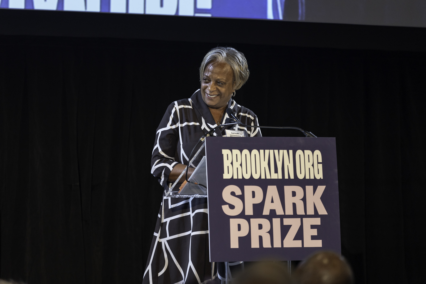 Woman speaking at a podium labeled "brooklyn.org spark prize.