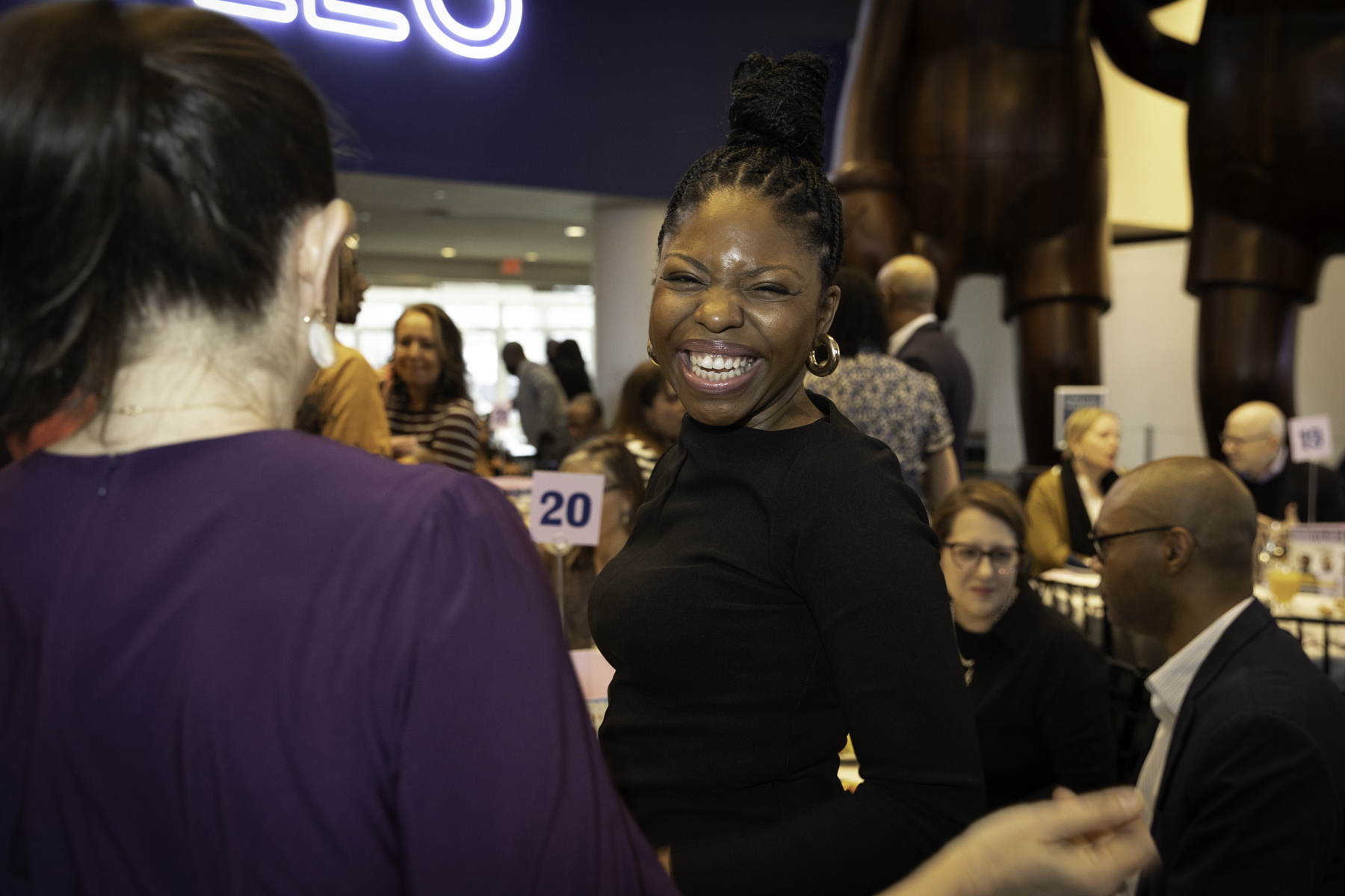 A woman with a joyful expression is engaged in a conversation at a social event.