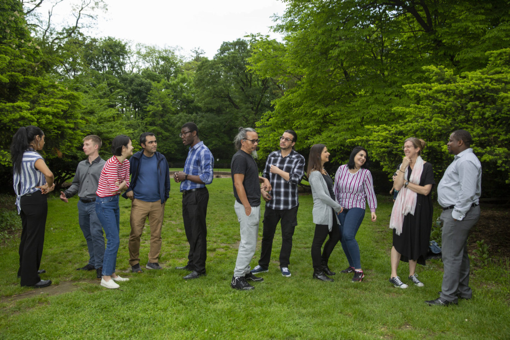 A group of diverse people engaging in a conversation outdoors in a park setting.