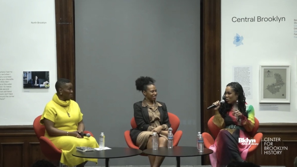 Three women engaged in a panel discussion at the center for brooklyn history, sitting on stage with microphones in a formal setting.