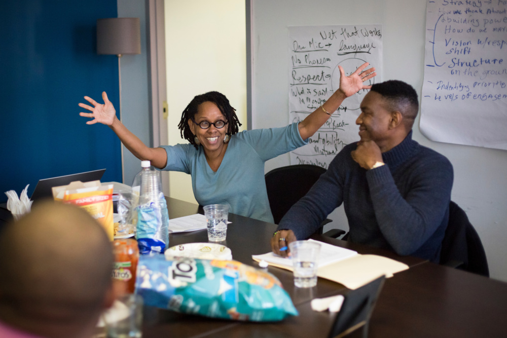 Two colleagues celebrating with a high-five in a meeting room with snacks and notes in the background.