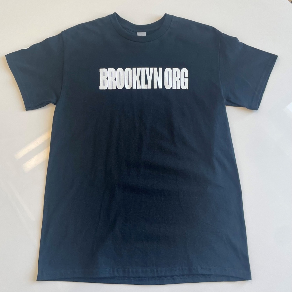 A black T-shirt laid flat on a surface with the text "BROOKLYN ORG" printed in white bold letters across the chest.