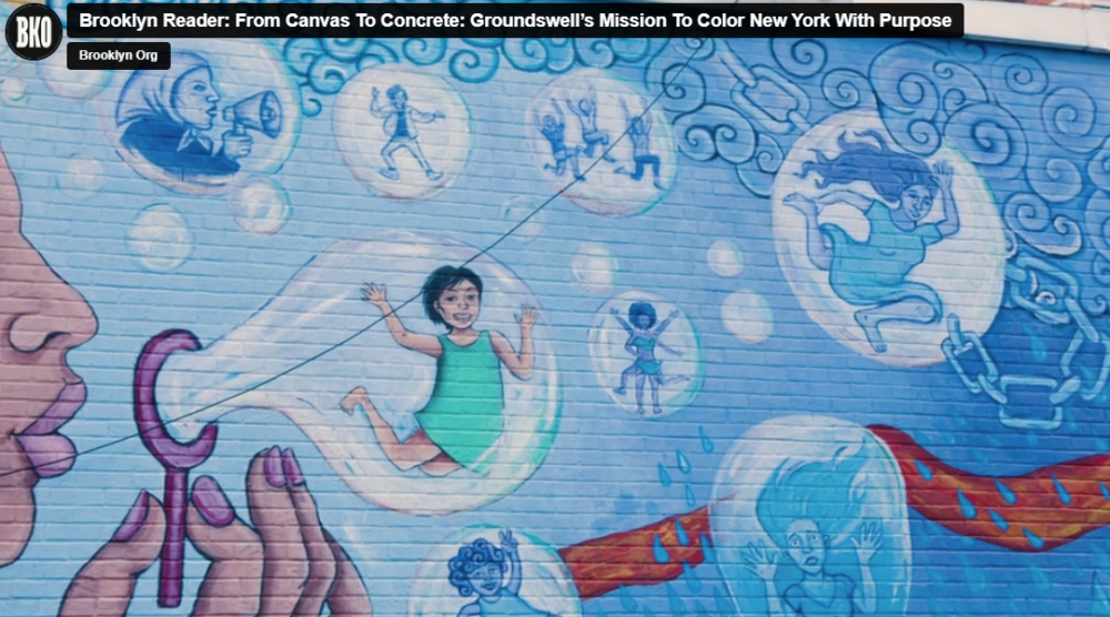 A mural on a brick wall depicts various scenes in bubbles, including a child in a green dress, figures enacting stories, and a hand blowing bubbles.