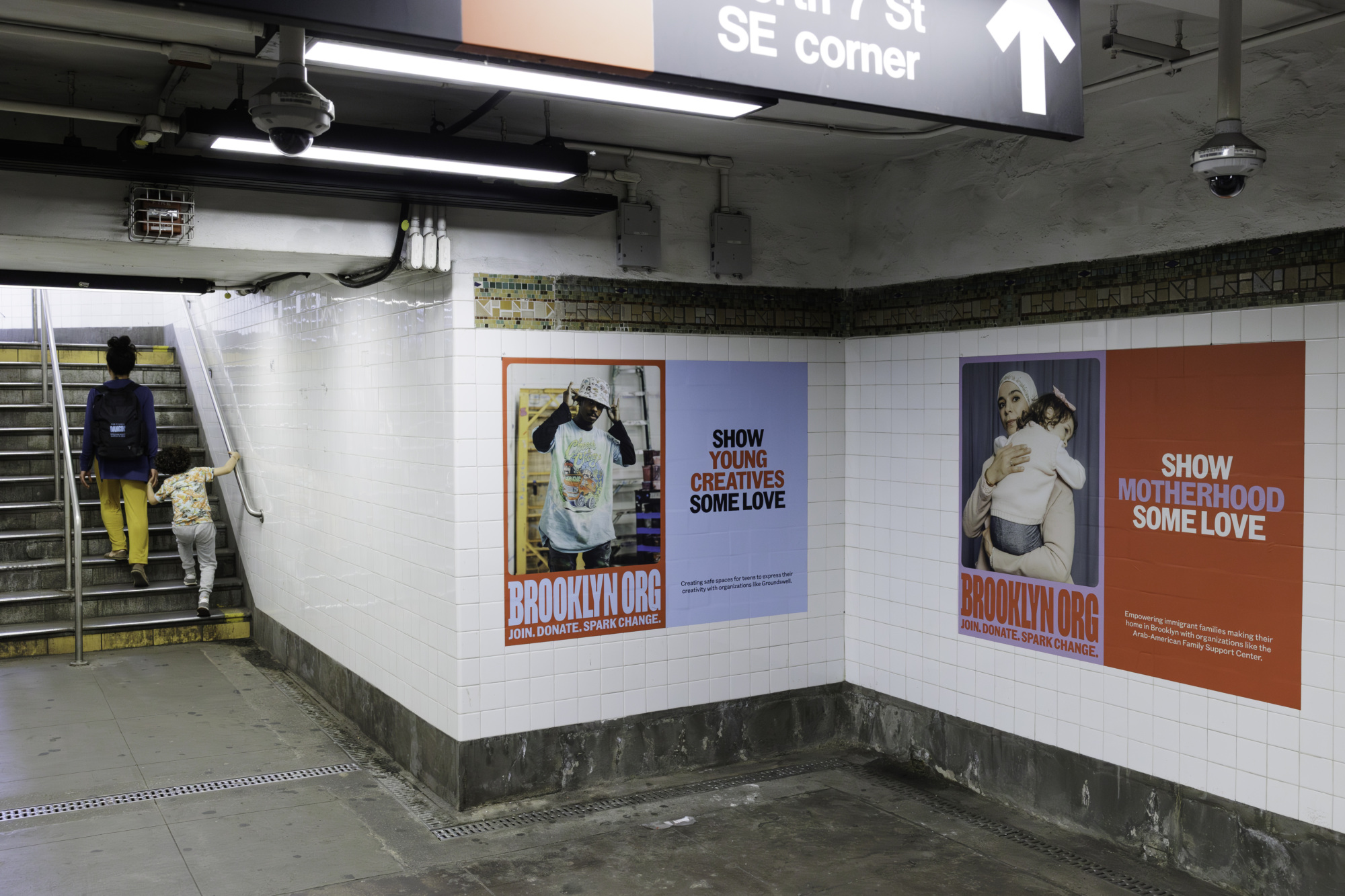 Two posters on a subway station wall. Left: "Show Young Creatives Some Love" message. Right: "Show Motherhood Some Love" message. A person and a child are ascending stairs to the left, encapsulating the spirit of community and urging us to give to Brooklyn.