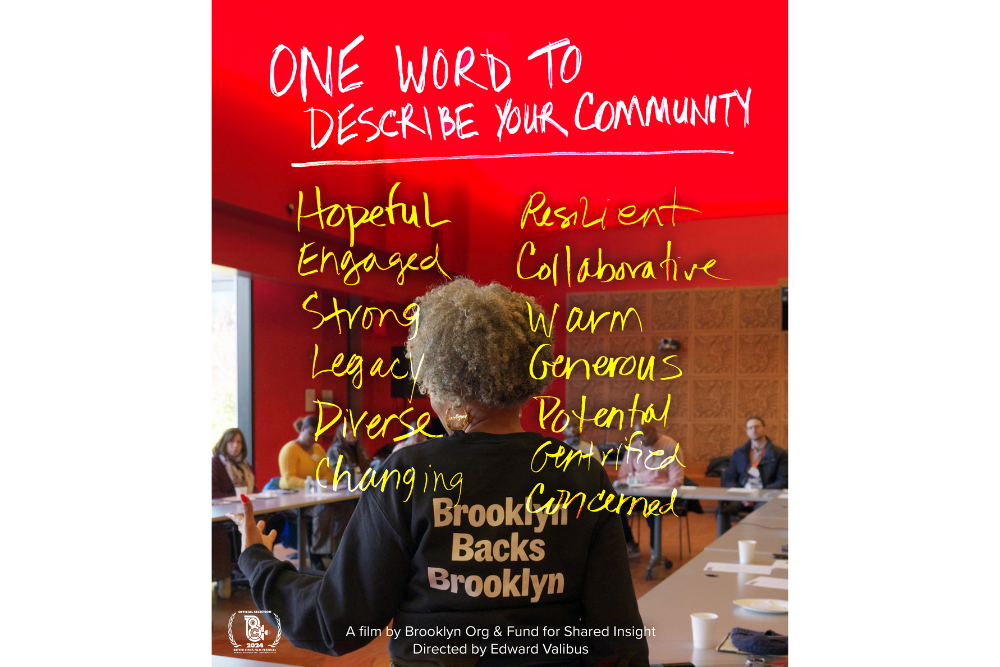 A person stands in front of a room of seated people. The red background above reads "One word to describe your community" with various words like "Hopeful" and "Resilient" written over the image.