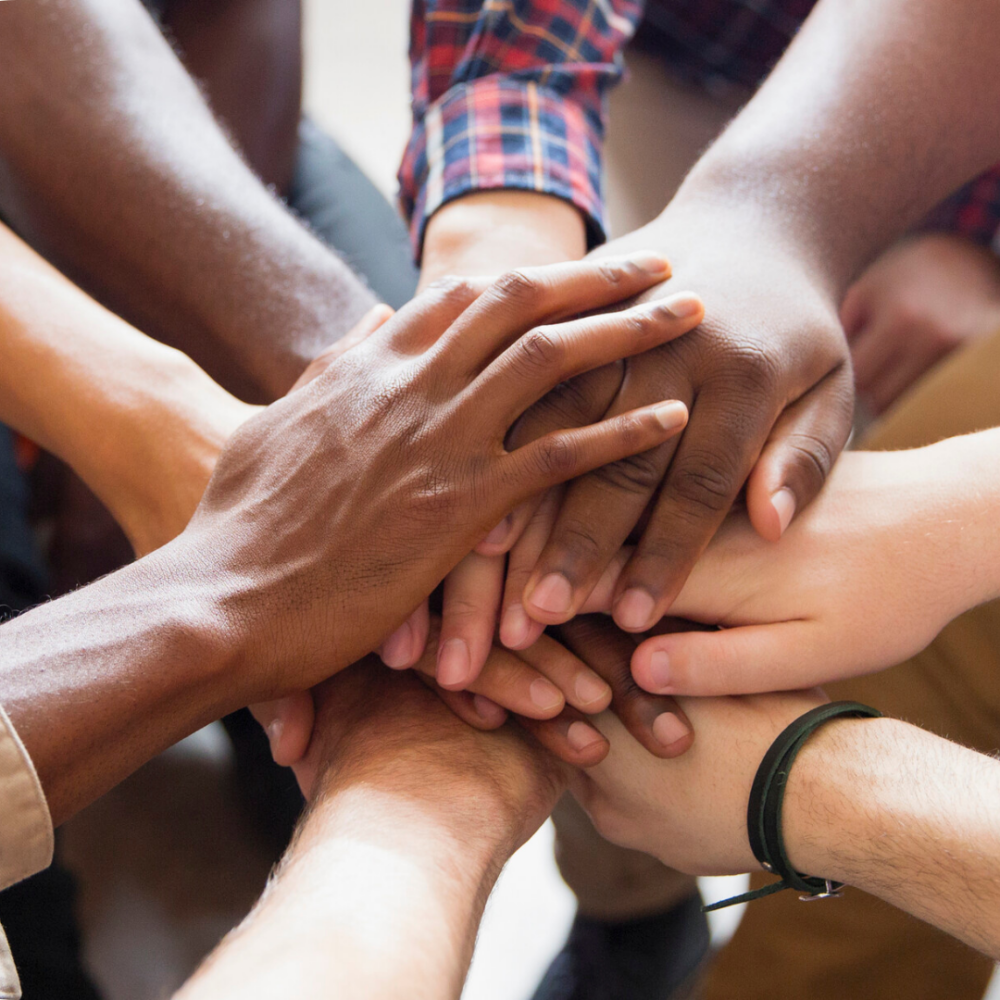 A close-up of multiple hands stacked in a pile, symbolizing unity and teamwork.