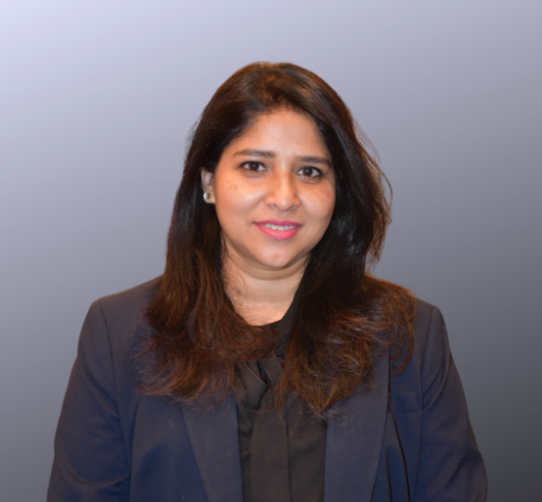 A person with long dark hair wearing a dark blazer and black top stands against a gradient background, facing the camera.