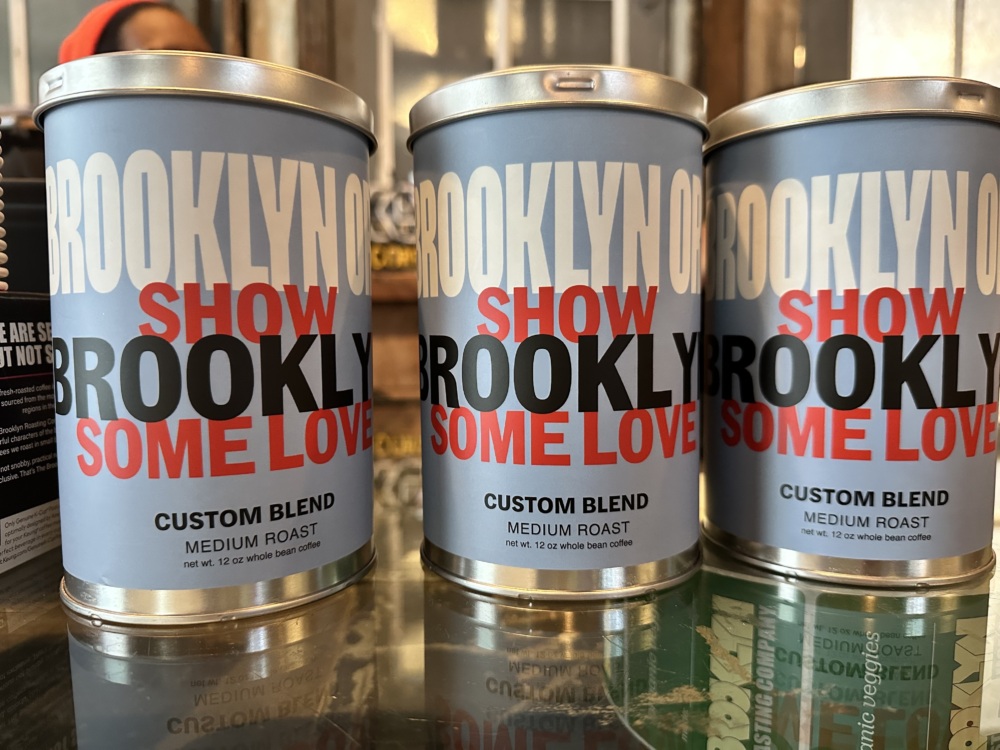 Three cans of medium roast coffee with "Brooklyn Show Some Love" written on the labels.