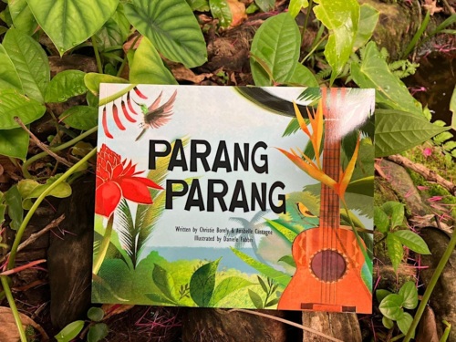 A children's book titled "Parang Parang" with vibrant illustrations of tropical plants, birds, and a guitar on the cover, set against a leafy background.