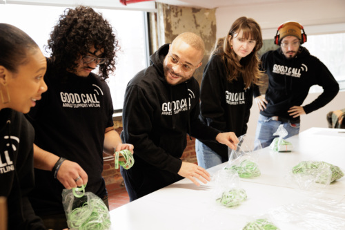 People in matching hoodies pack green cords into bags at a table in a casual setting.