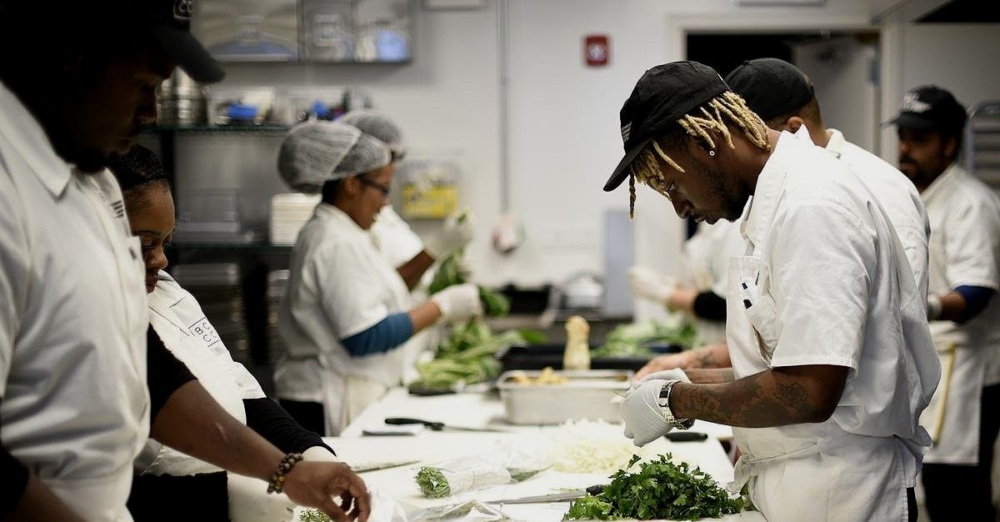 Culinary team focused on preparing herbs and vegetables in a commercial kitchen.