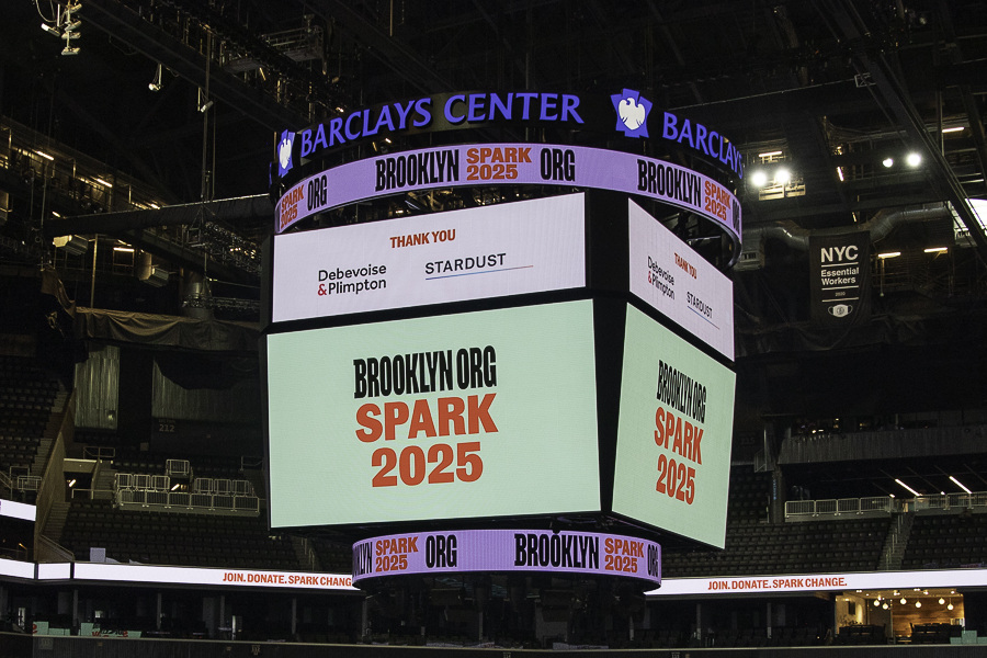 An empty basketball arena with a large screen displaying "BROOKLYN TOOK IT SPARK 2025" at the Barclays Center.