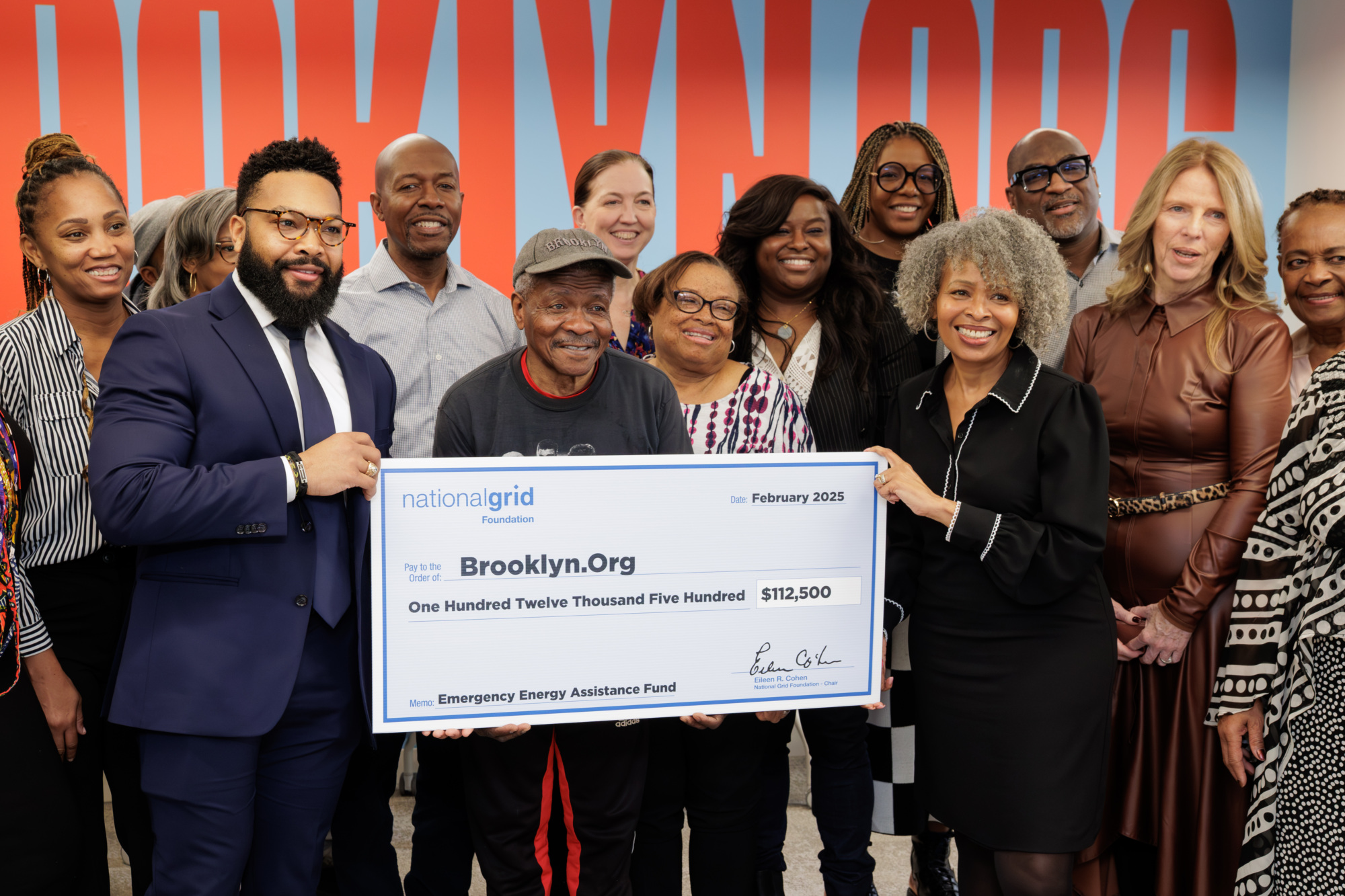 A group of people smiling and holding a large check for $112,500 from National Grid to Brooklyn.Org for an emergency energy assistance fund.