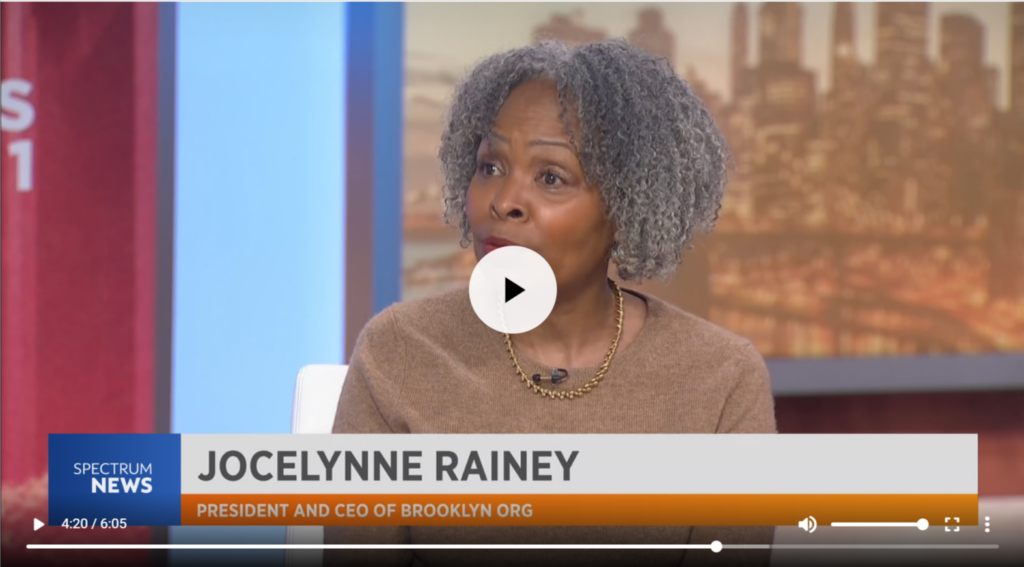 A woman with gray curly hair speaks on a news program, with the text "Jocelynne Rainey, President and CEO of Brooklyn Org" displayed on the screen.