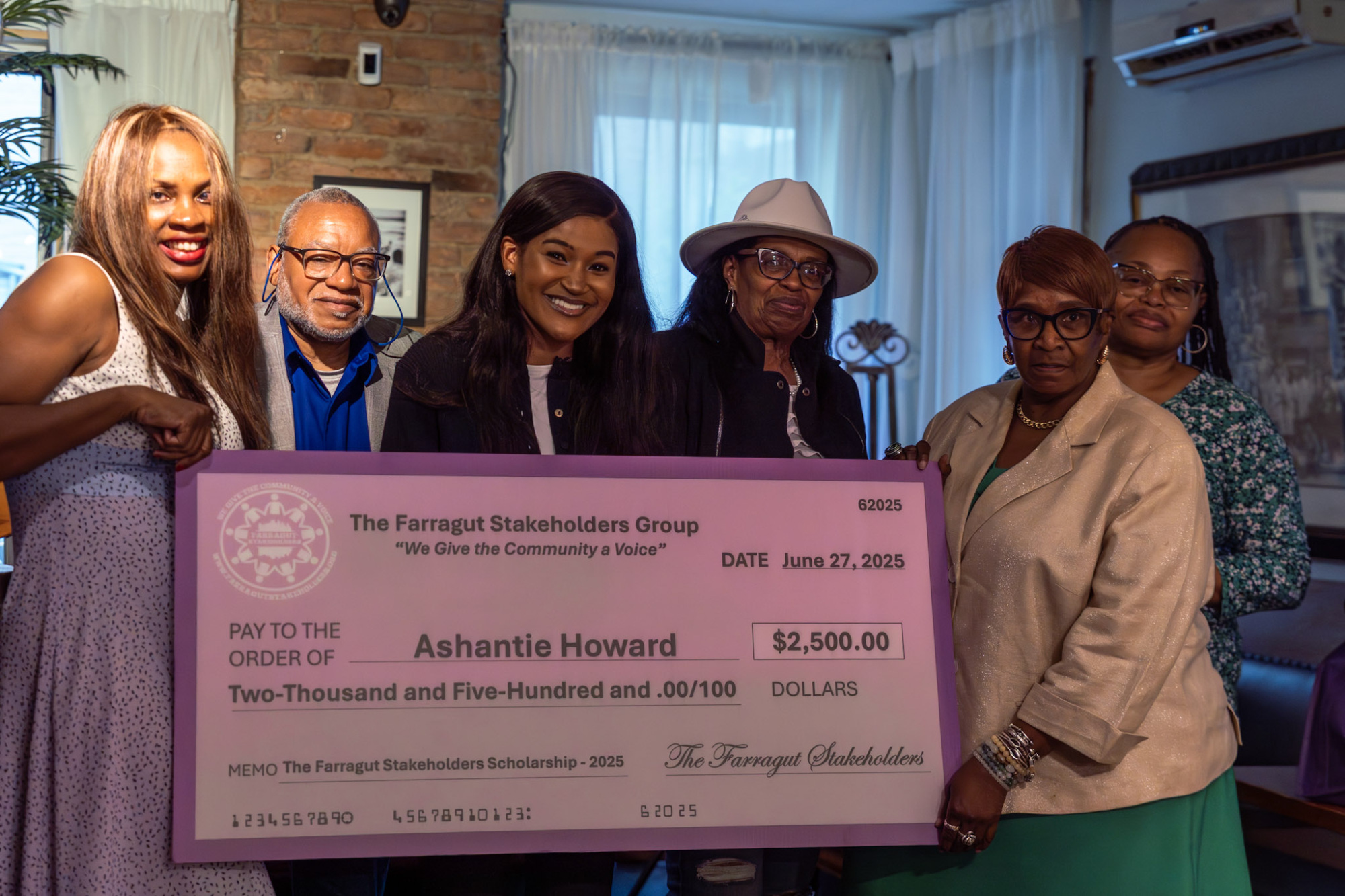 Six people stand indoors holding a large ceremonial check for $2,500 made out to Ashantie Howard from The Farragut Stakeholders Group, dated June 27, 2025.