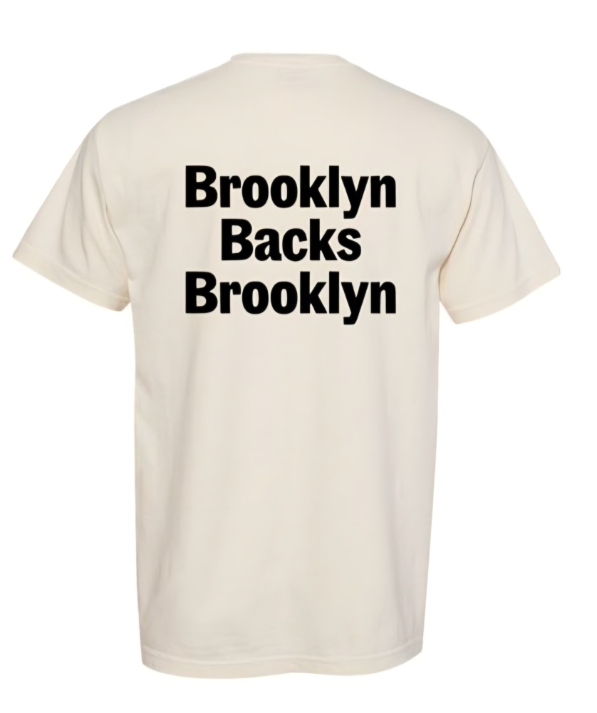 A plain white T-shirt with the text "Brooklyn Backs Brooklyn" printed in bold black letters on the back.